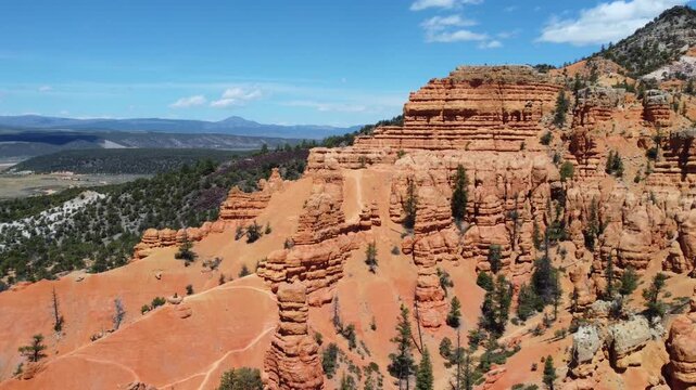 Cinematic drone footage flying over Dixie National Forest in Utah. Stunning aerial view of dramatic red rock spires, hoodoos, and geological formations similar to Bryce Canyon. 