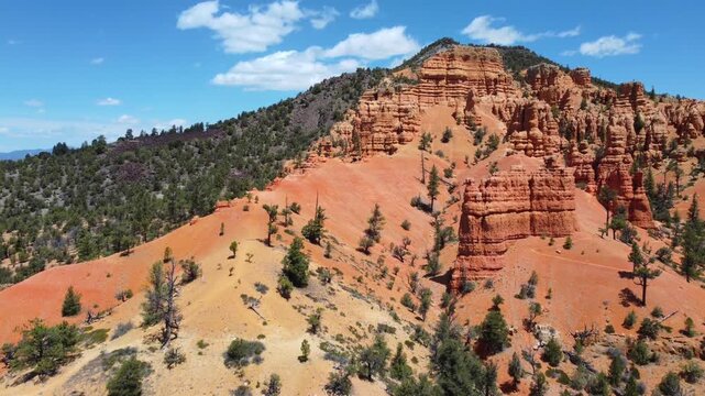 Cinematic drone footage flying over Dixie National Forest in Utah. Stunning aerial view of dramatic red rock spires, hoodoos, and geological formations similar to Bryce Canyon. 