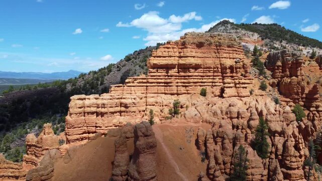 Cinematic drone footage flying over Dixie National Forest in Utah. Stunning aerial view of dramatic red rock spires, hoodoos, and geological formations similar to Bryce Canyon. 