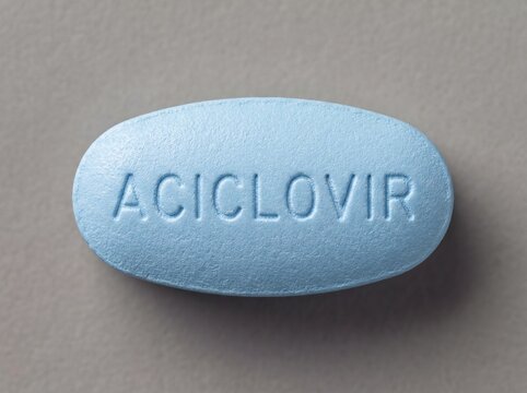 A professional photography close-up shot of a blue oval tablet with ACICLOVIR clearly stamped on the front, resting on a plain neutral background.