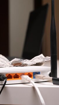 Vertical video hand placing dollar bills and coins on a white internet router, illustrating the concept of internet bills, subscription costs, and paying for connectivity services
