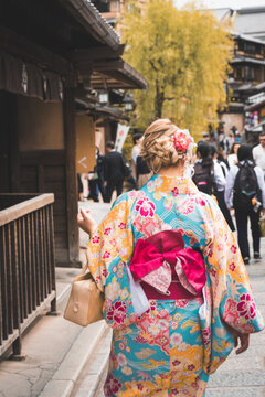 Blonde woman wearing a kimono walks along the busy streets in Gion district of Kyoto Japan