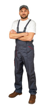 Handyman with crossed arms posing in grey bib overalls and cap.