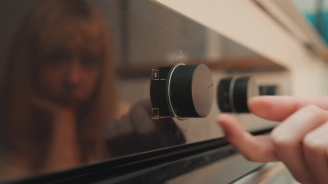 White student baker turns oven dial, latenight prep with anxious reflection in oven glass, closeup fingertip adjusting temperature, warm kitchen lighting, experimental recipe practice, focused nervous