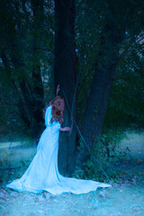 Fototapeta premium fantasy woman in white gown against tree in twilight