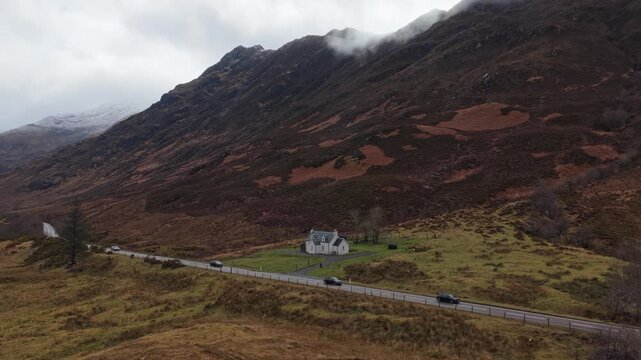 Cars driving on road through glencoe valley in the scottish highlands