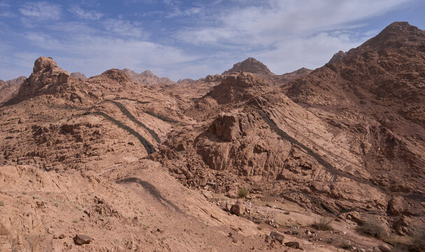 Dramatic mountain landscape in national park Saint Katherine Protectorate, Egypt. Rugged red‑hued mountains. Black colors of magmatic rock. Dikes or dykes. Hiking in Sinai.