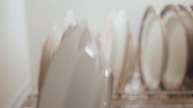 Drying and organizing dinnerware for peace. Neatly placing and drying porcelain dishes after cooking. Meticulously arranging and drying fine porcelain plates as part of calming routine