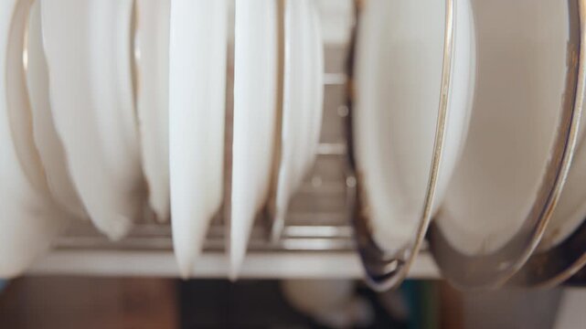 Plates drying carefully. Porcelain dishes arranged neatly. Detailed scene of dishes drying after meal preparation. Photograph capturing careful placement of porcelain plates in dish rack after cooking