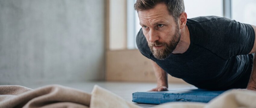 Athletic man doing pushups fitness workout in home gym training core strength and endurance with intense concentration and determination, healthy lifestyle active lifestyle concept.
