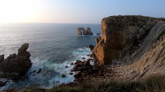 Costa Quebrada near Liencres, Cantabria, Spain. Waves breaking against the rocks during a calm summer evening on the Atlantic coast.