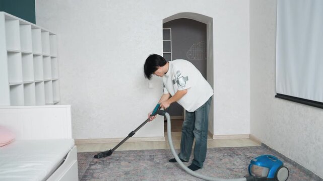 Man sweeps dust from bedroom. Person diligently vacuums bedroom carpet to clear dust and debris. Individual performs regular vacuuming of bedroom carpet to eliminate dust and dirt buildup