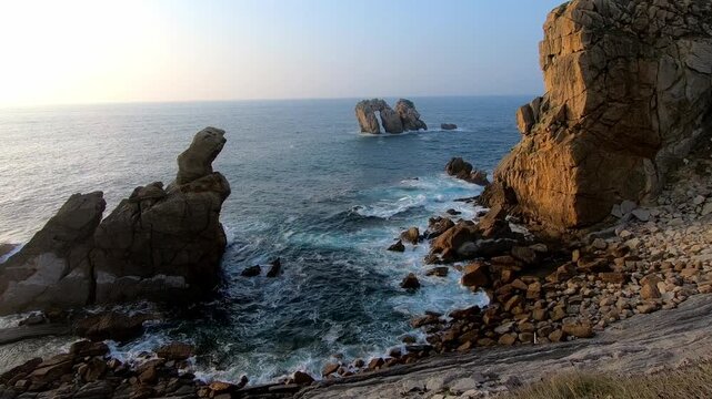 Scenic coastal view of rocky cliffs, ocean waves and the iconic sea stacks of Costa Quebrada near Liencres, Cantabria, Spain.