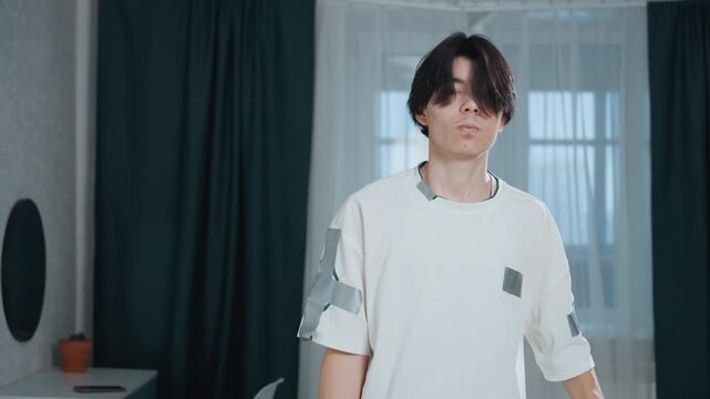 Man demonstrating vacuum cleaner effectiveness in room. Young individual using vacuum to clean living space efficiently. Young man demonstrates power of vacuum during cleaning in bright living room
