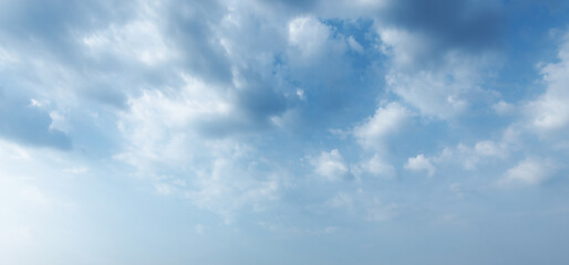 Fototapeta premium Cloudy sky, natural background photo texture. A soft blue sky filled with scattered white clouds forming a serene, airy cloudscape perfect as a calming backdrop for design, web, and nature projects