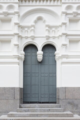 Obraz premium Elegant arched double door set into a white, ornate classical Church facade with decorative moldings and granite steps; minimal, symmetrical architectural detail conveying history calm