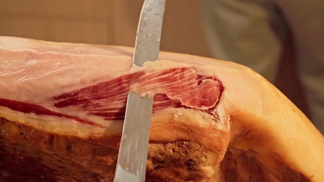 Primer plano de maestro jamonero cortando finas lonchas de jam&oacute;n ib&eacute;rico espa&ntilde;ol.