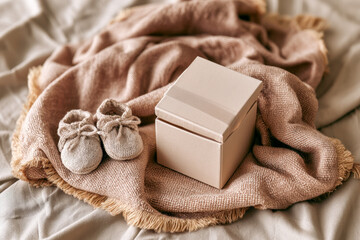 Fototapeta premium Baby Booties and Gift Box on Soft Pink Blanket