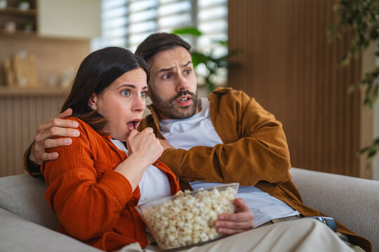 Frightened couple watching scary movie at home