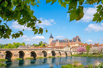 Naklejka premium Under a bright sky, Gien’s bridge and castle rise above the calm Loire, blending history, stone and the gentle spirit of the region into a serene, timeless and vibrant landscape