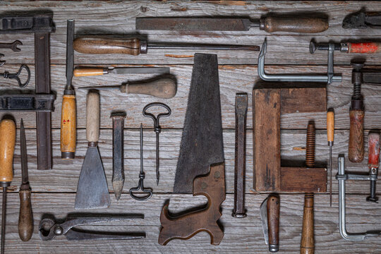 Vintage hand tools arranged on weathered wooden workbench