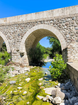 Ancient stone bridge spanning a creek with green algae