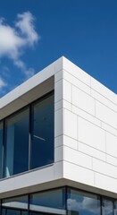 Obraz premium Modern White Building Facade with Large Glass Windows Under Blue Sky.