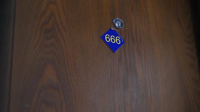 A closing door with the number "666" in a hotel or apartment