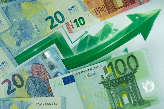 EURO strengthening against other currencies, a green arrow and an upward chart symbolizing its increased value on the foreign exchange market. Few european banknotes 100, 20, 10 euro