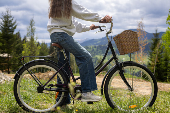 Woman Riding Vintage Bicycle in Mountains. Woman rides a classic bicycle with wicker basket through grassy mountain scenery, suggesting outdoor travel, leisure, and active lifestyle.