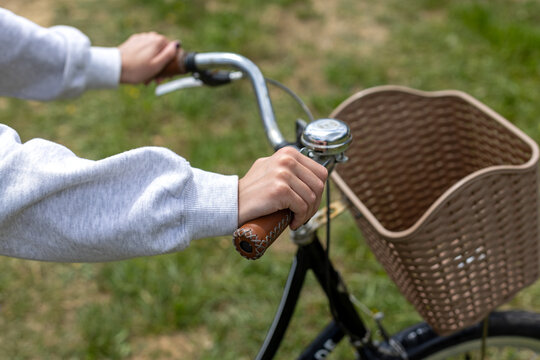 Hands Holding Vintage Bicycle Handlebars. Close-up of hands gripping vintage bicycle handlebars with bell and basket, showing outdoor cycling, leisure, and eco transport.