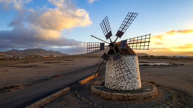 Cinematic drone shot of old Tefia windmill in deserted Spanish landscape at sunset, Fuerteventura, Canary Islands Wild volcanic scenery. authentic Spain, wall art print .copy space sky