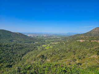 Fototapeta premium Hills and trees stretch out with a view of a city. Roses, Spain
