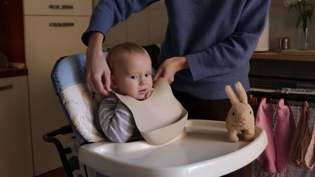 Mother putting feeding bib on resisting toddler