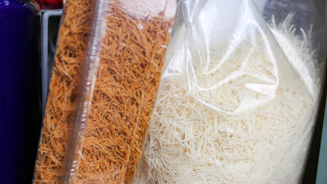 Packaged roasted golden and raw white shredded kataifi phyllo dough on a shelf. baking ingredient.