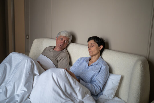 Senior husband and wife sitting in bed frustrated discussing intimate and sexual problems in relationships, upset married elderly couple dealing with low passion and healthcare issues at older age