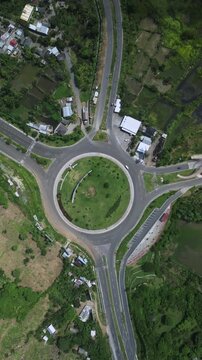 Country Intersection With Green Central Patch. View Of Rural Roundabout With Lush Surroundings. Aerial Perspective Showcasing Rural Roundabout Encircled By Vegetation And Scattered Rural Houses