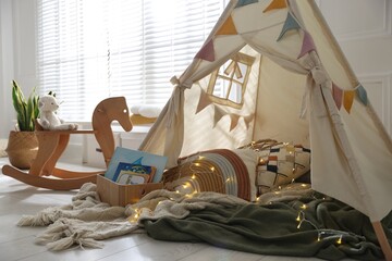 Cute wigwam with fairy lights and toys in stylish child's room © New Africa