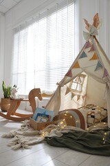 Cute wigwam with fairy lights and toys in stylish child's room © New Africa