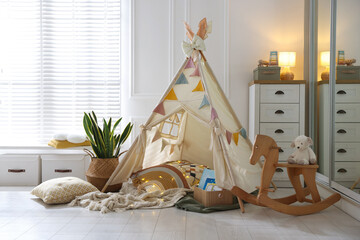 Cute wigwam with fairy lights and toys in stylish child's room © New Africa