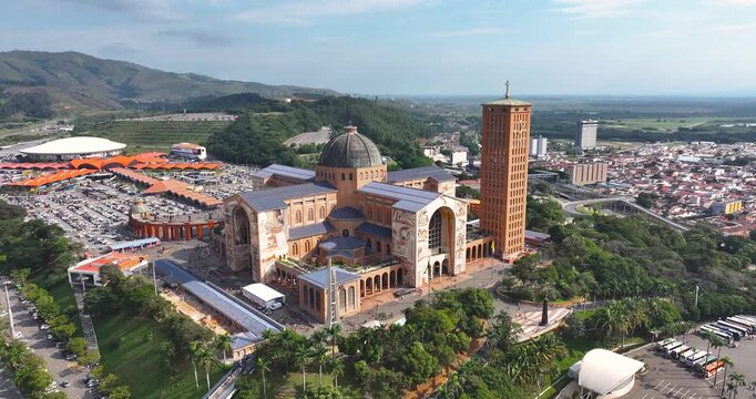 4K aerial drone view of the National Shrine of Aparecida, Brazil, showing iconic Catholic basilica, pilgrimage site and cityscape.