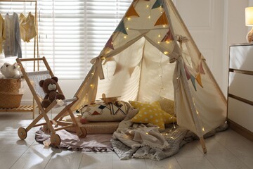 Cute wigwam with fairy lights and toys in stylish child's room © New Africa