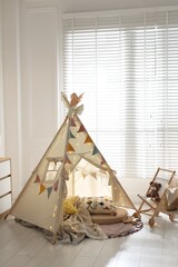 Cute wigwam with fairy lights and toys in stylish child's room © New Africa