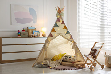 Cute wigwam with fairy lights and toys in stylish child's room © New Africa