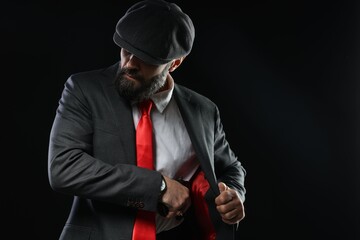 Naklejka premium Mafia. Man pulling gun out of jacket on dark background. Space for text