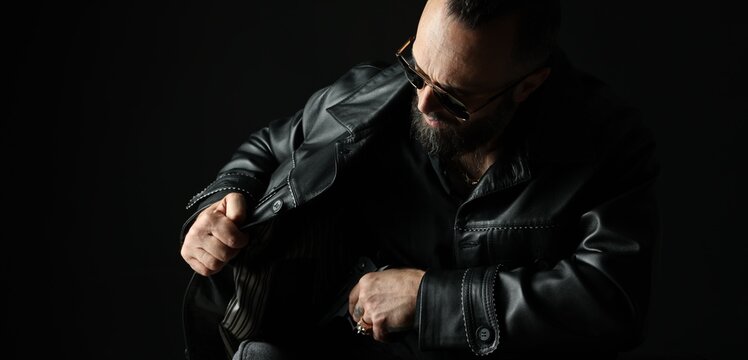 Mafia. Man in sunglasses pulling gun out of jacket on dark background