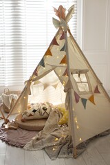 Cute wigwam with fairy lights and toys in stylish child's room © New Africa