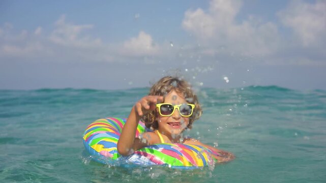 A happy child is having fun in the sea during the summer holidays. Slow motion