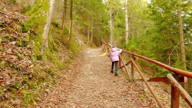 Little beautiful girl walks near Belianska Cave, is stalactite cave in Slovak part of Tatra mountains, largest and only one open to public in Tatras. Vysoke Tatry, Tatranska Kotlina, Lendak, Slovakia.