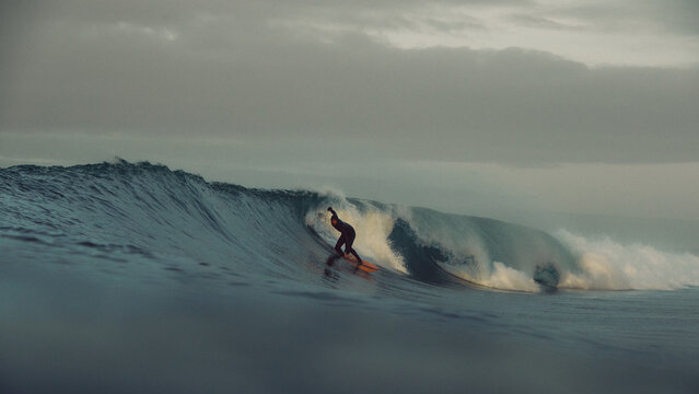 surfer large tubular wave sunrise atlantic ocean